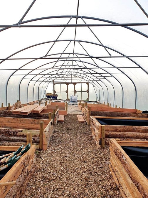 a greenhouse with wooden raised beds